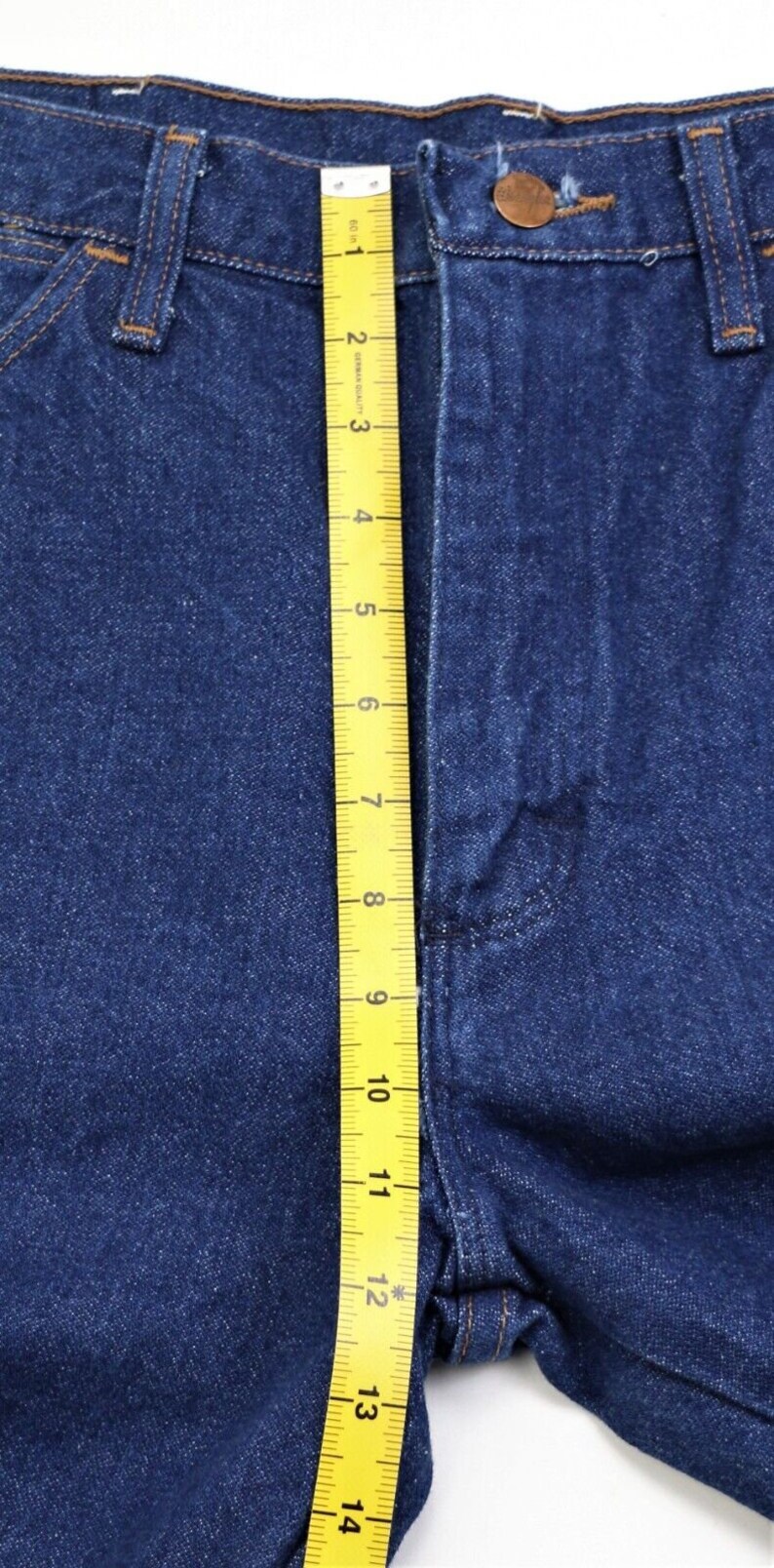 May include: A close-up of a pair of blue denim jeans with a yellow measuring tape running vertically along the side seam. The tape measures up to 14 inches.