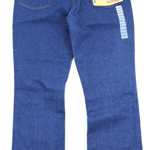 May include: A pair of blue denim jeans with a bootcut leg opening. The jeans have a back pocket with a stitched 'W' logo. The jeans have a tag attached that says 'Bootcut Regular Fit Wrangler'.