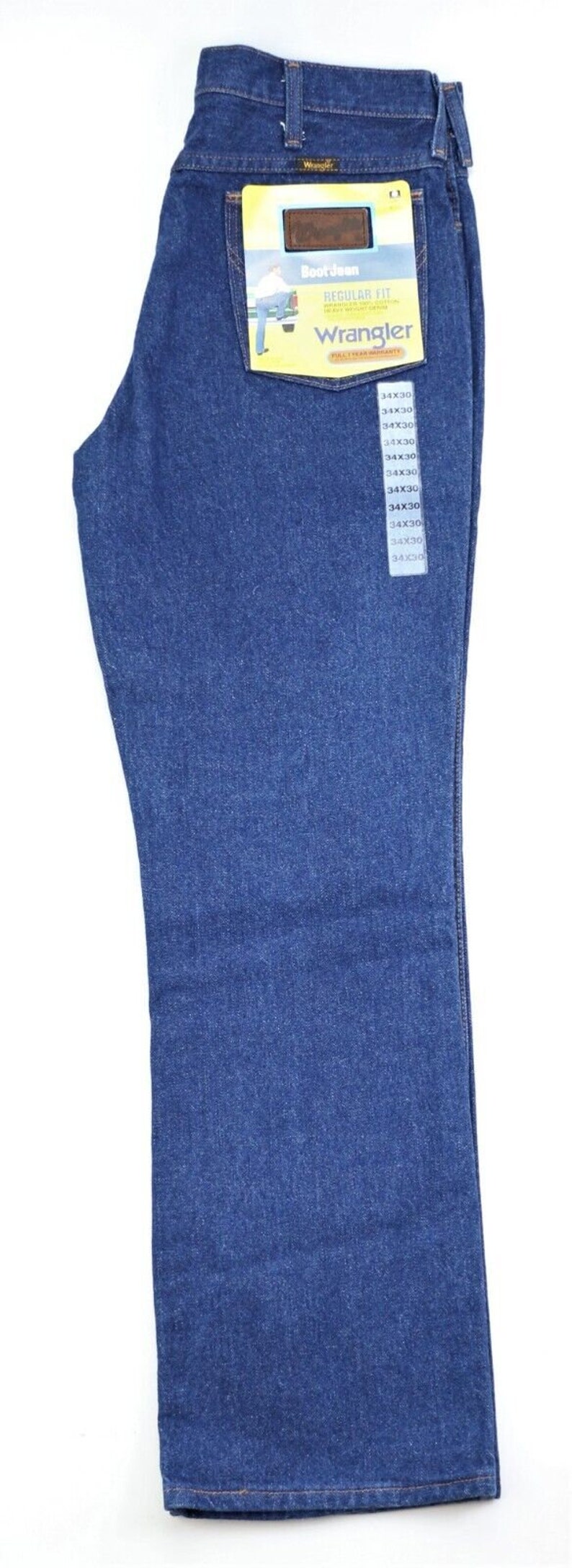 May include: A pair of blue denim jeans with a yellow and brown label that says "Boot Jean Regular Fit Wrangler". The label also has a picture of a man wearing the jeans. The jeans are size 34x30.