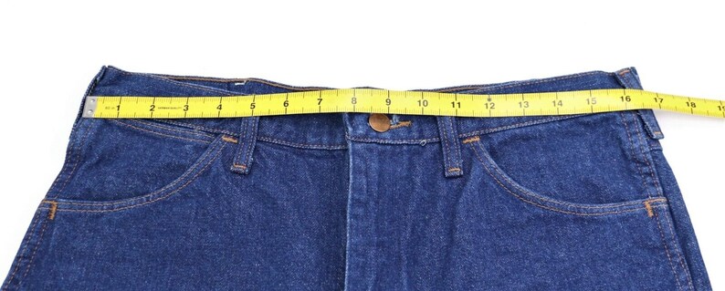 May include: Blue denim jeans with a yellow measuring tape around the waist. The tape measures 16 inches.