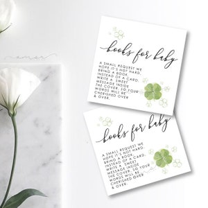 May include: Two white cards with green shamrock designs and the text "books for baby". The text on the cards reads: "A small request we hope it's not hard. Bring a book, instead of a card. Write a sweet message inside the cover, so your words will be cherished over & over."