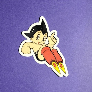 May include: A sticker featuring a cartoon character with black hair, a white shirt, and red rocket boots. The character is flying through the air with a finger pointing up.