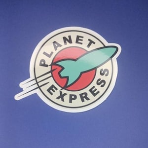 Könnte beinhalten: Ein weißer runder Aufkleber mit einem roten, weißen und blauen Raketen-Design. Der Text "Planet Express" ist um die Rakete herum geschrieben.