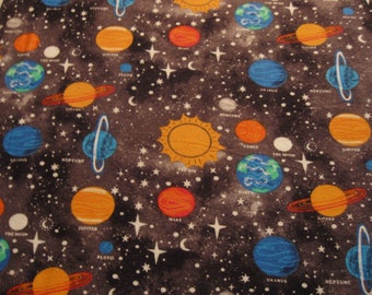 May include: A dark blue fabric with a repeating pattern of planets and stars. The planets are in various colors, including orange, red, blue, and green. The fabric is perfect for a space-themed project.