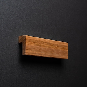 Peut inclure: Une poignée de porte en bois de forme rectangulaire avec une finition brun foncé.