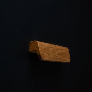 Könnte beinhalten: Ein Holz-Schubladengriff mit einer geschwungenen Form und einer natürlichen Holzoptik.