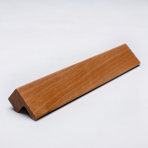 May include: A wooden corner shelf with a natural wood grain. The shelf is light brown and has a right-angle shape. Designed to fit into a corner, it offers a space-saving storage solution. The shelf is approximately 20 cm long.