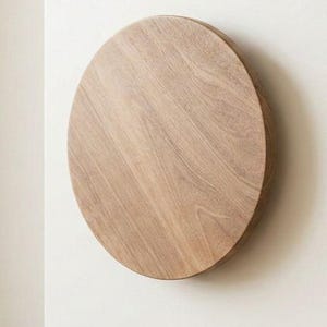 Pode incluir: Um puxador de armário oval de madeira montado numa porta de armário branca. O puxador tem um acabamento de grão de madeira natural e está ligeiramente elevado da superfície da porta. A porta do armário é de cor neutra.