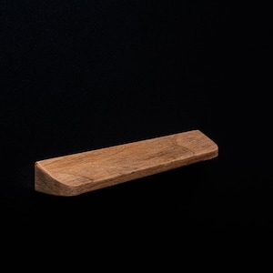 May include: A wooden shelf with a curved edge, made of light brown wood. The shelf is isolated against a black background.