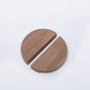 以下が含まれることがあります： 木製の半円形のドアノブが2つ。それぞれに自然な木目があります。ノブは並べて設置するように設計されており、完全な円になります。