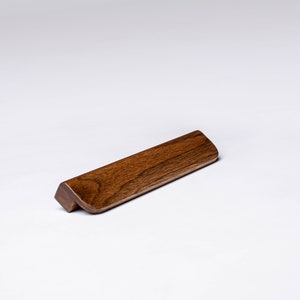 May include: A dark brown wooden cabinet pull with a curved design.