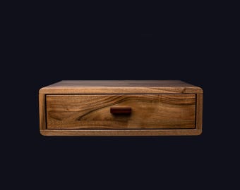 May include: A wooden nightstand with a single drawer and a dark wood finish. The drawer has a small, rectangular, brown handle.