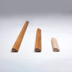 Könnte beinhalten: Drei Holzmöbelkomponenten in verschiedenen Größen. Die Teile bestehen aus verschiedenen Holzarten, mit Farben von hellem Beige bis mittlerem Braun. Jedes Teil hat eine abgerundete Kante und eine flache, abgewinkelte Oberseite.