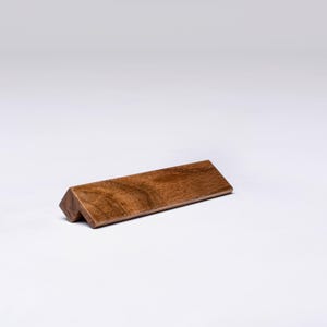 Puede incluir: Un letrero rectangular de madera con un borde biselado. El letrero está hecho de madera marrón oscura con veta de madera natural.