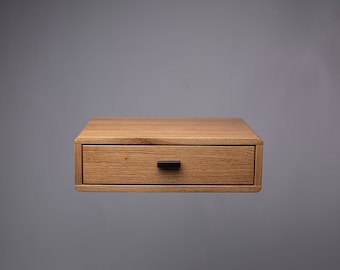 May include: A light wood floating nightstand with a single drawer and a black drawer pull.