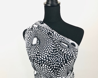 May include: A black and white one-shoulder dress with a swirling polka dot pattern. The dress has a fitted bodice and a flowing skirt.