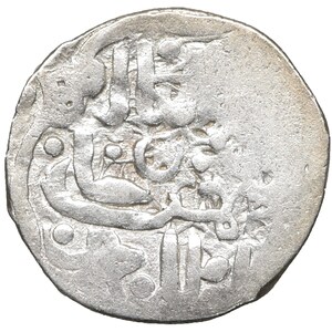 Könnte beinhalten: Eine silberne Münze mit aufwendiger arabischer Schrift und Designs. Die Oberfläche der Münze weist Gebrauchsspuren auf, mit sichtbaren Details der Inschriften und Muster. Die Münze hat eine kreisförmige Form mit einem leicht unregelmäßigen Rand.