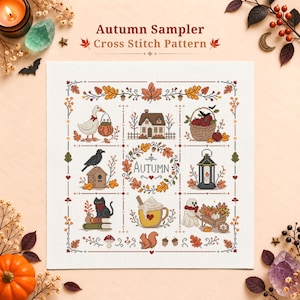 May include: An Autumn Sampler cross stitch pattern featuring a grid of nine seasonal illustrations including a goose with a pumpkin, a house, a basket of apples, a crow on a birdhouse, a central autumn wreath, a lantern, a cat on books, a mug, and a ghost.