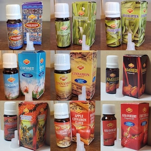 以下が含まれることがあります： 10本の小さなガラス瓶が、それぞれ異なるエッセンシャルオイルが入っています。瓶は3列3本ずつ、一番下の列には4本目の瓶が置かれています。各瓶には、「ココナッツ」、「シナモン」、「シトロネラ」、「ユーカリ」など、オイルの名前が書かれたラベルが付いています。