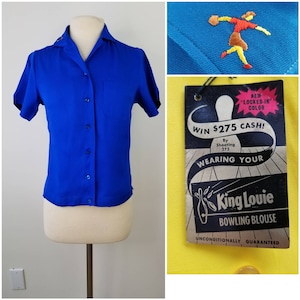 Peut inclure: Une chemise de bowling bleu royal à manches courtes et à fermeture boutonnée. La chemise a une petite poche sur la poitrine gauche. La chemise porte une étiquette qui dit "King Louie Bowling Blouse" et "Gagnez 275 $ en espèces ! En tirant 275 En portant votre".