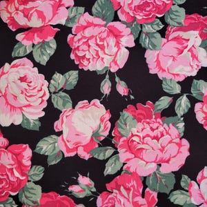 May include: Black fabric with a pink and white floral pattern. The fabric features a repeating pattern of roses with pink petals and white centers.
