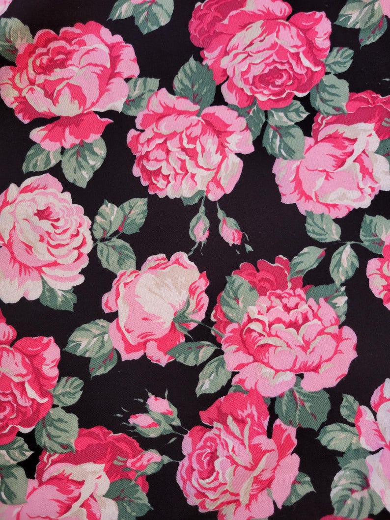 May include: Black fabric with a pink and white floral pattern. The fabric features a repeating pattern of roses with pink petals and white centers.