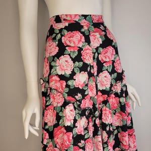 May include: A black maxi skirt with a pink and green floral print. The skirt has a ruffled hem and a fitted waist.