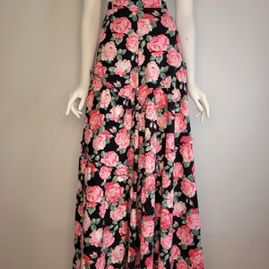 May include: A long black skirt with a pink and green floral print. The skirt has a tiered design and a high waist.