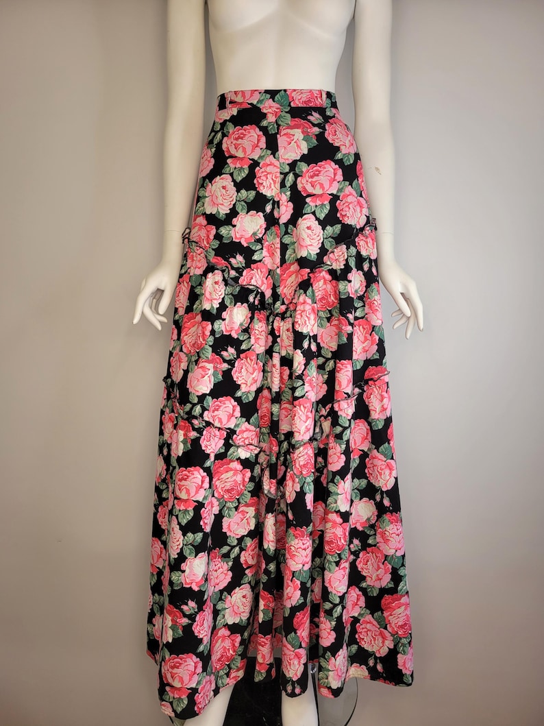May include: A long black skirt with a pink and green floral print. The skirt has a tiered design and a high waist.