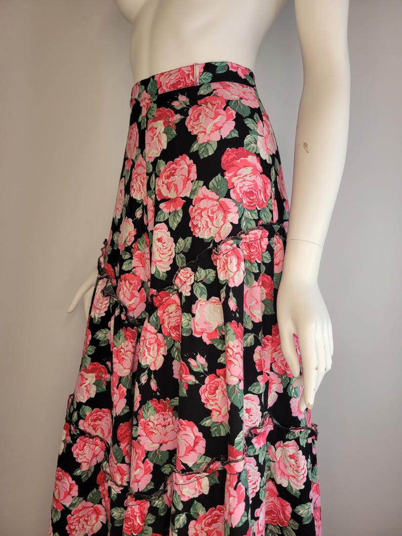May include: A black maxi skirt with a pink and green floral print. The skirt has a tiered design and a ruffled hem.