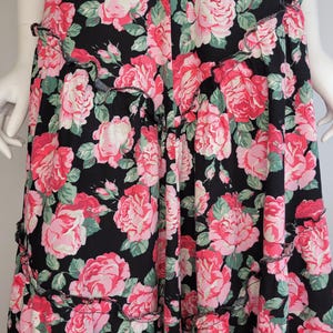 May include: A black maxi skirt with a pink and green floral print. The skirt has a ruffled hem.