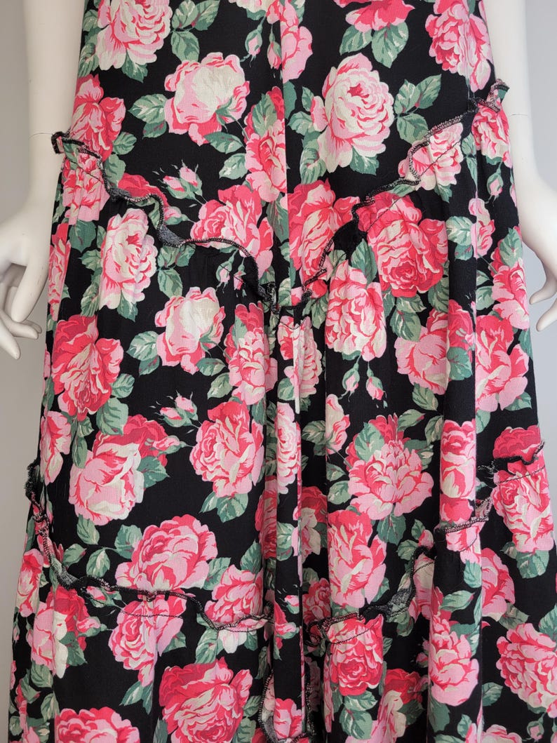 May include: A black maxi skirt with a pink and green floral print. The skirt has a ruffled hem.