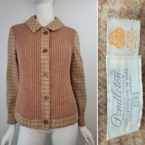 May include: A tan and beige button-up cardigan featuring a ribbed knit front panel and plaid patterned sleeves, collar, and trim. The interior label reads Pendleton Woolen Mills, 100% Virgin Wool, Portland, Oregon, with a size 14 tag.