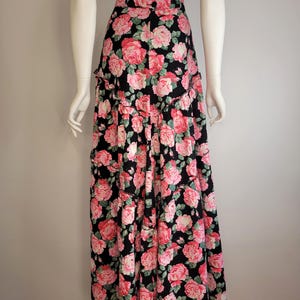 May include: A long black skirt with a pink and green floral print. The skirt has multiple tiers and a ruffled hem.