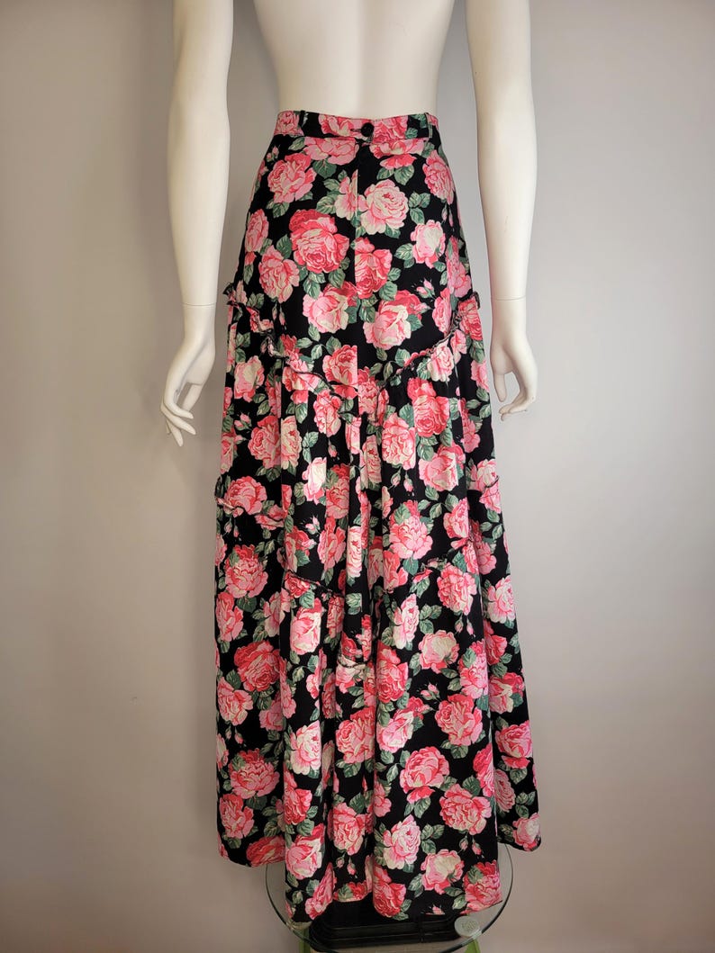 May include: A long black skirt with a pink and green floral print. The skirt has multiple tiers and a ruffled hem.