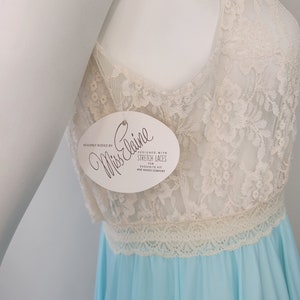 May include: A light blue and white lace nightgown with a white tag that reads "Heavenly Bodies by Miss Elaine Designed with Stretch Laces for Exquisite Fit and Added Comfort".