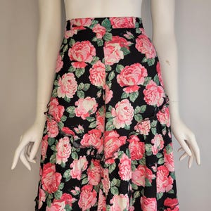 May include: A black maxi skirt with a pink floral print. The skirt has a ruffled hem and a high waist.