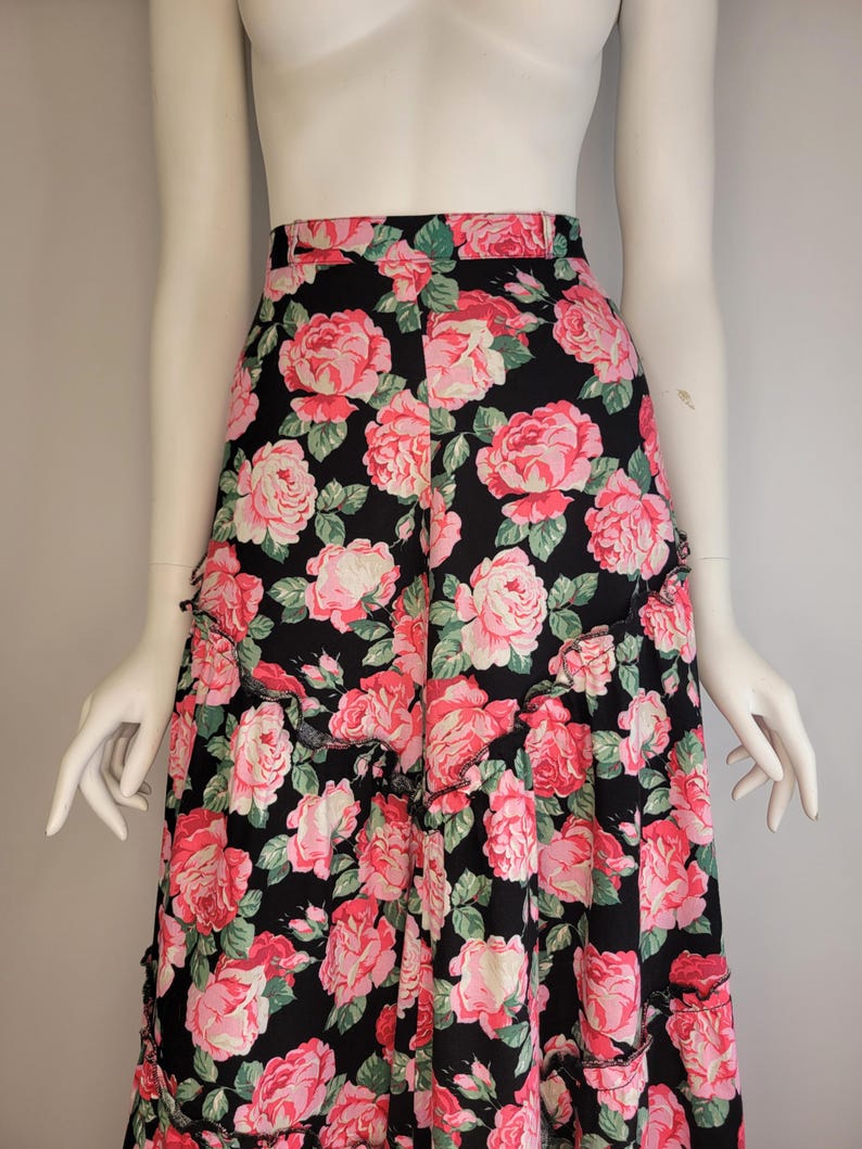 May include: A black maxi skirt with a pink floral print. The skirt has a ruffled hem and a high waist.