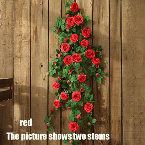 May include: Two stems of artificial red roses with green leaves cascade down a wooden background. The roses are in full bloom, and the leaves are a deep green. The text "red" and "The picture shows two stems" are visible.
