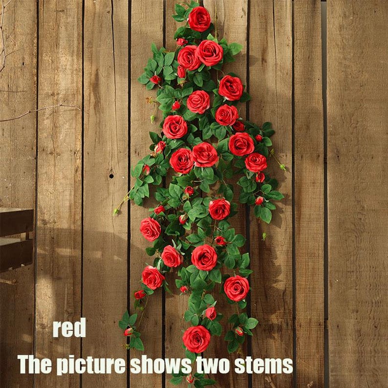 May include: Two stems of artificial red roses with green leaves cascade down a wooden background. The roses are in full bloom, and the leaves are a deep green. The text "red" and "The picture shows two stems" are visible.