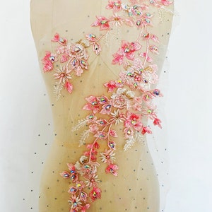 Può includere: Applique floreale rosa con strass iridescenti e perle su un tessuto di rete trasparente. L'applique è a forma di vite con fiori e foglie. Il testo "2#" è visibile nell'angolo in alto a destra dell'immagine.