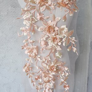 May include: A delicate floral lace applique with 3D flowers in shades of peach and ivory. The lace is perfect for adding a touch of elegance to wedding dresses, bridal accessories, or other special occasion garments.