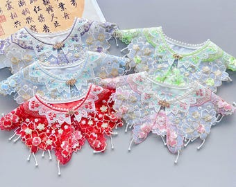 May include: Five different lace collars with pearl accents. The collars are in shades of blue, green, pink, and red. Each collar has a floral design and a small pearl button.