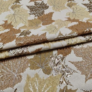 May include: A close-up of a fabric with a pattern of gold and brown leaves. The fabric has a textured, embossed look.
