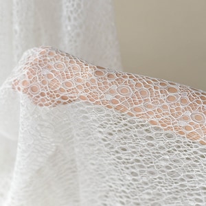 May include: White lace fabric with a delicate circular pattern. The fabric is soft and sheer, making it ideal for a variety of crafting projects.
