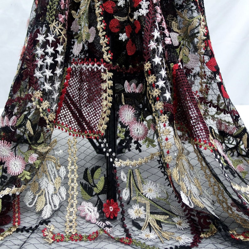Puede incluir: Tela de malla negra con dise&ntilde;os florales bordados en tonos rojos, rosas, blancos y dorados. La tela tiene un patr&oacute;n delicado e intrincado.