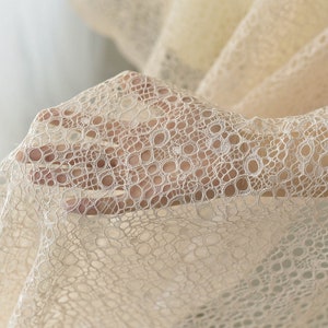 May include: Beige lace fabric with a delicate circular pattern. The fabric is soft and sheer, with a subtle shimmer.