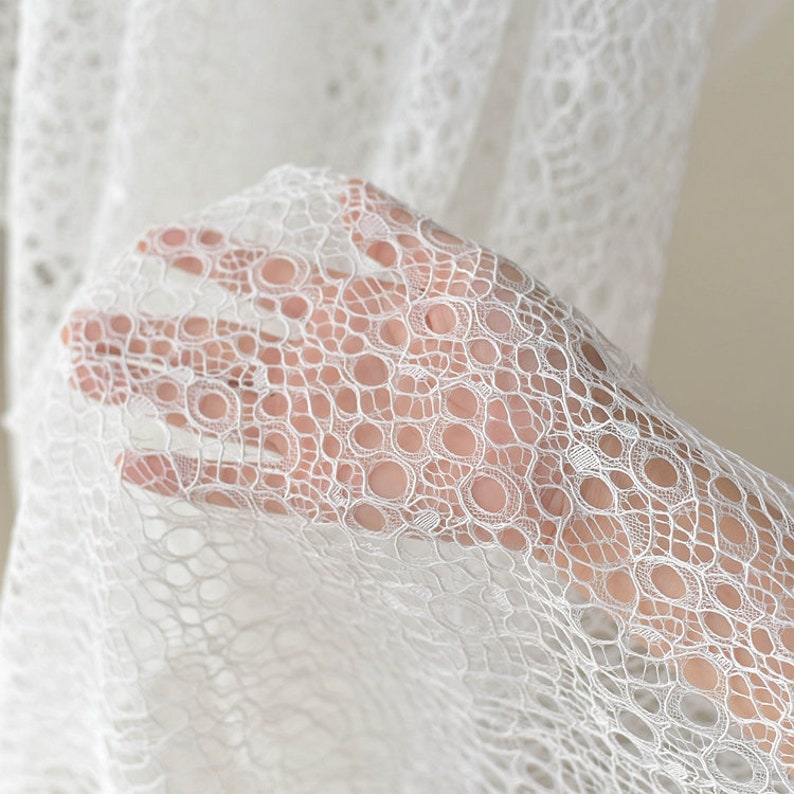 May include: White lace fabric with a delicate circular pattern. The lace is soft and sheer, with a delicate texture.