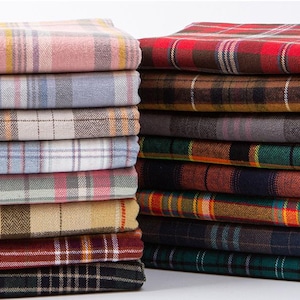 May include: Two stacks of folded fabric featuring various plaid and tartan patterns. The left stack includes light pink, blue, beige, and maroon tones. The right stack displays darker colors such as red, brown, grey, green, and navy blue.