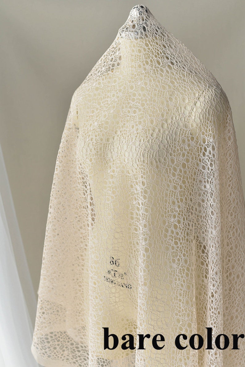 May include: A close-up of a beige lace fabric with a circular pattern. The fabric is draped over a white mannequin. The text "bare color" is printed on the fabric.